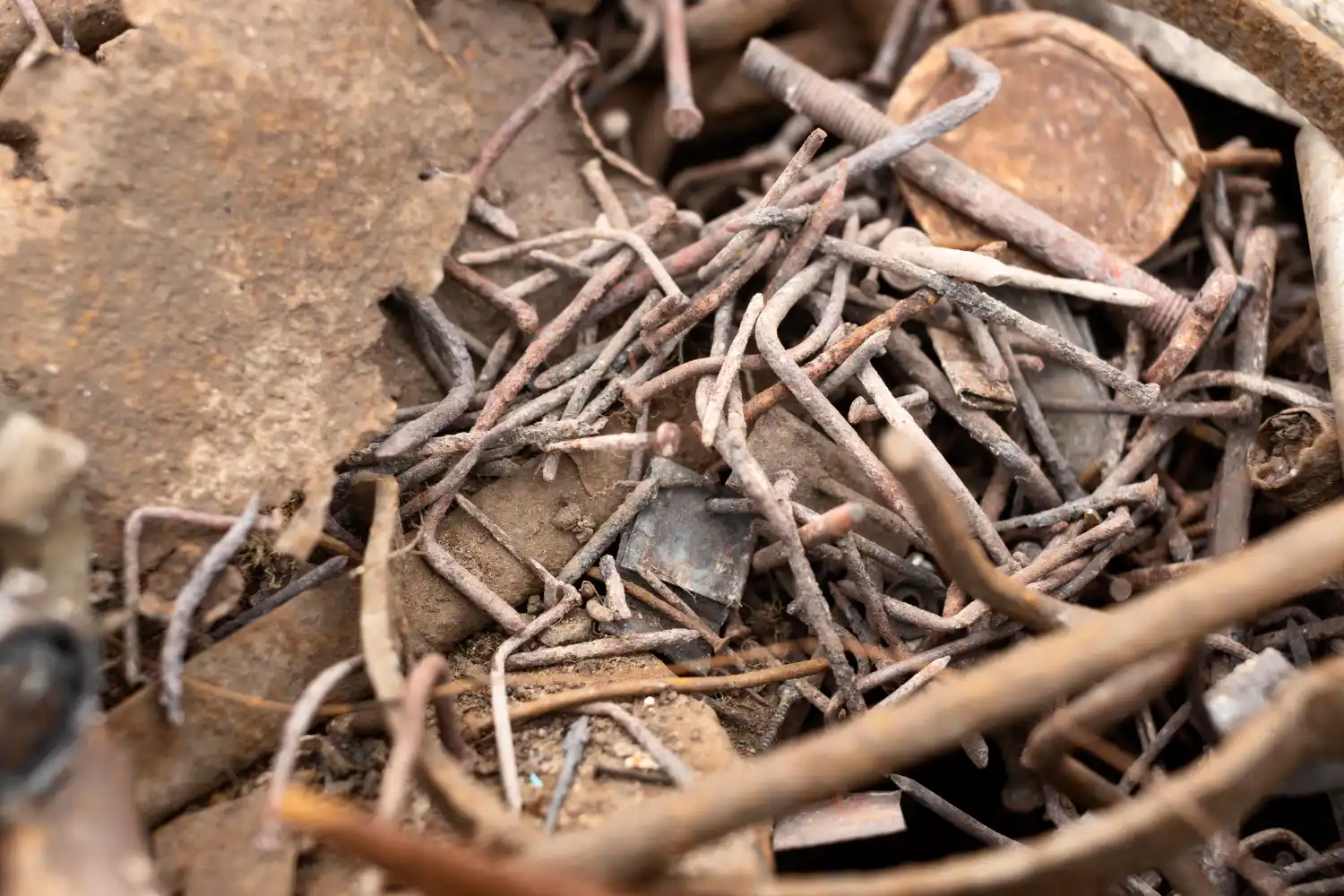 Close-up of rusty ferrous metal scrap, including nails and steel pieces ready for recycling.