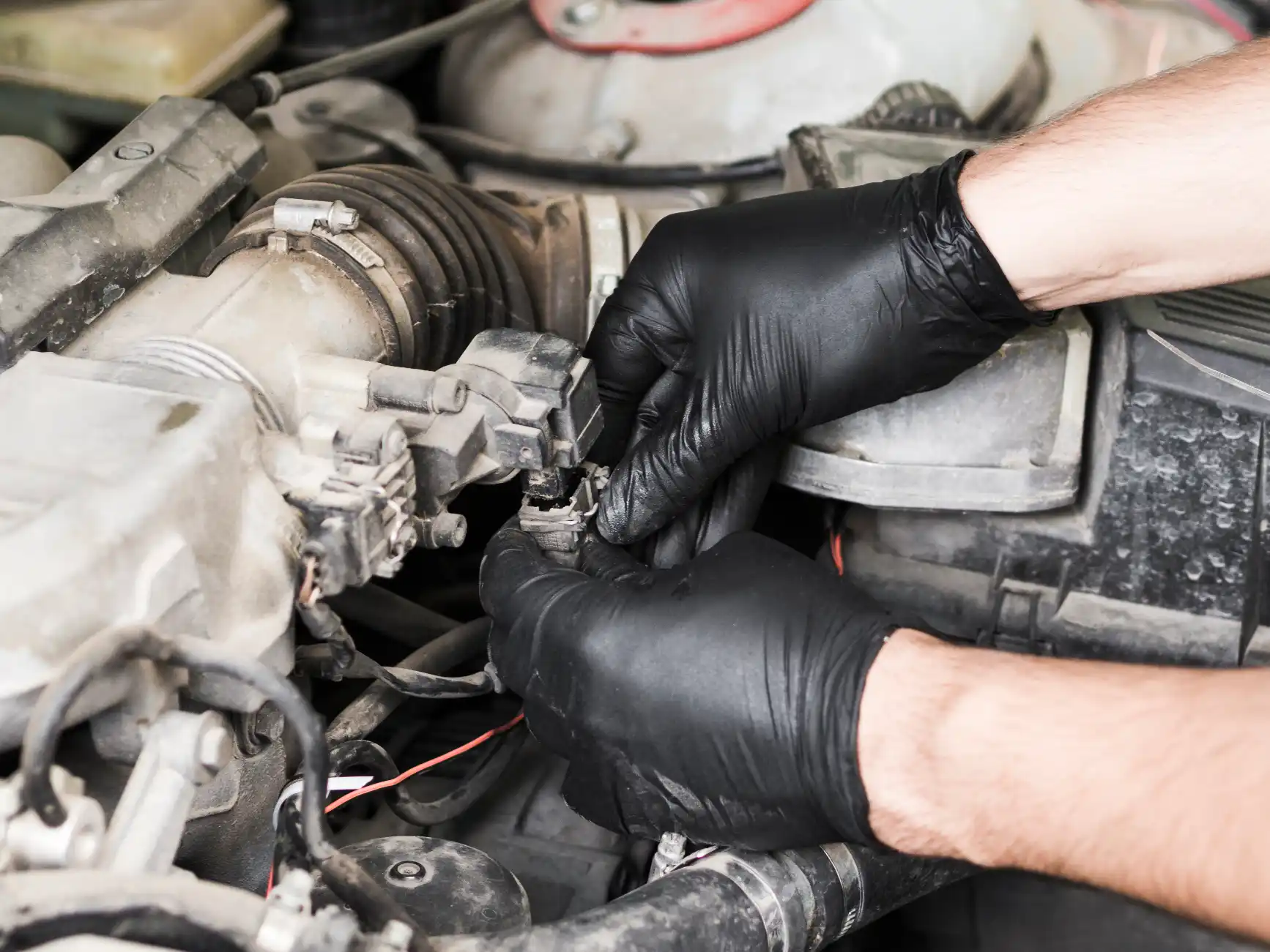 Mechanic in black gloves removing engine wiring components for DPF scrap recycling service in Sydney